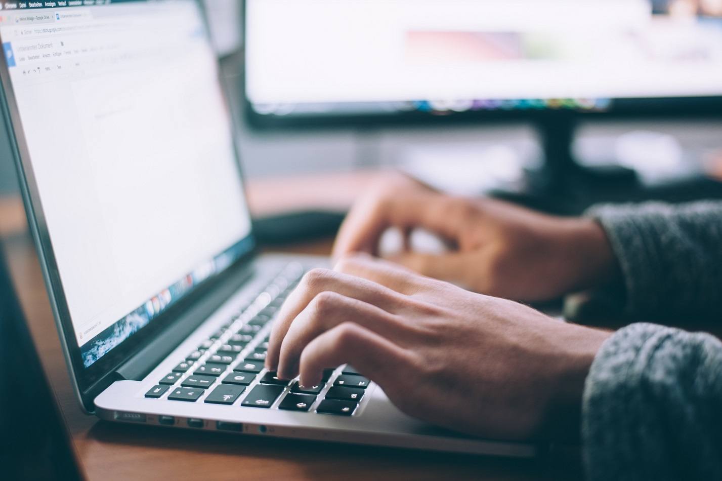 two hands typing on a laptop keyboard